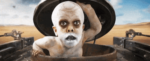 A Child With White Paint On His Face Is Sticking Out Of A Hole In The Ground GIF