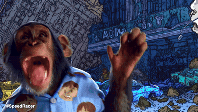 A Chimpanzee Wearing A Blue Shirt With Faces On It Stands In Front Of A Building That Says Radio GIF