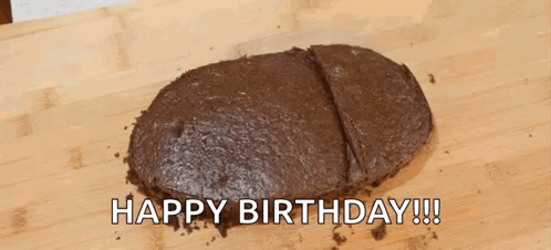 A Chocolate Cake Is Sitting On A Wooden Cutting Board With The Words `` Happy Birthday '' Written Above It . GIF