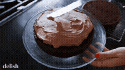 A Chocolate Cake With Frosting On A Glass Plate GIF