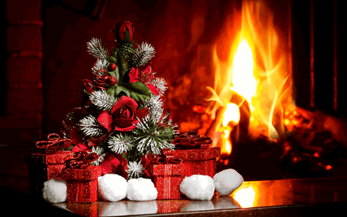 A Christmas Tree And Presents Are In Front Of A Fireplace GIF