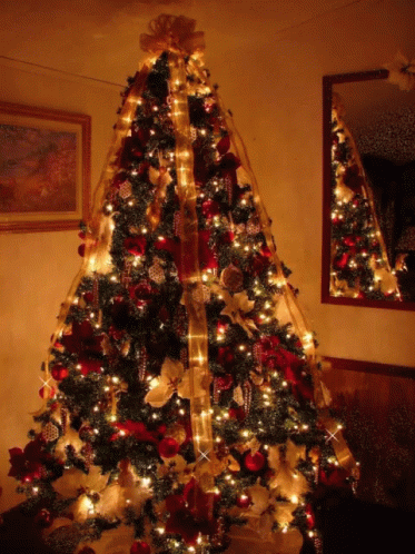 A Christmas Tree Decorated With Red And Gold Ornaments And Lights GIF