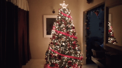 A Christmas Tree With A Star On Top Is Lit Up In A Room GIF