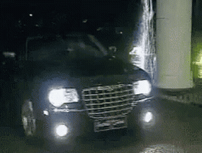 A Chrysler Car Is Parked At Night With Its Headlights On GIF