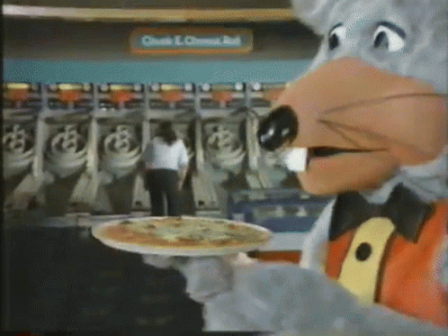 A Chuck E Cheese Mascot Is Holding A Pizza On A Tray . GIF