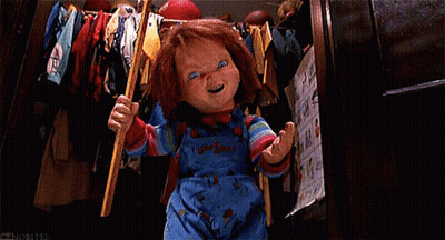 A Chucky Doll Is Holding A Bat In A Closet And Smiling . GIF
