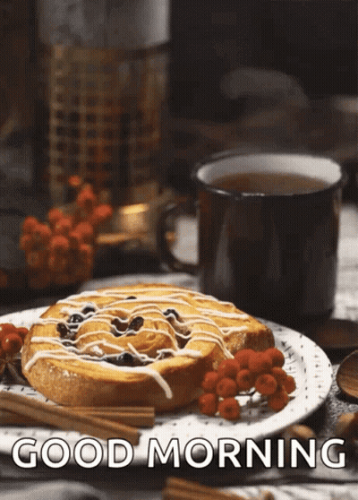 A Cinnamon Roll On A Plate Next To A Cup Of Tea With The Words Good Morning Written Below It GIF