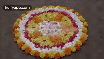 A Circular Pattern Made Of Flowers And Rice On The Ground GIF
