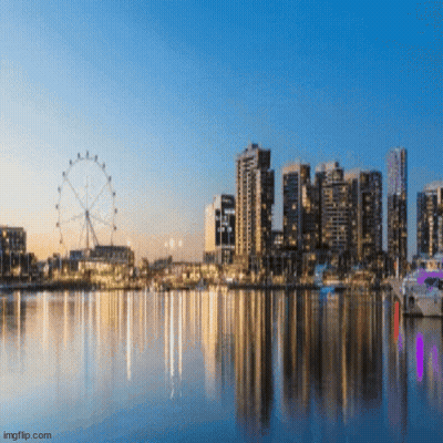A City Skyline With A Ferris Wheel In The Foreground And A Body Of Water In The Foreground GIF