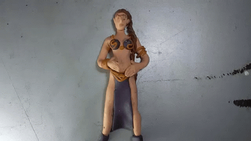 A Clay Figurine Of A Woman With A Black Skirt GIF