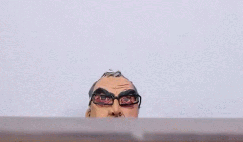 A Clay Statue Of A Man Wearing Glasses And A Hoodie Is Sitting On A Table . GIF