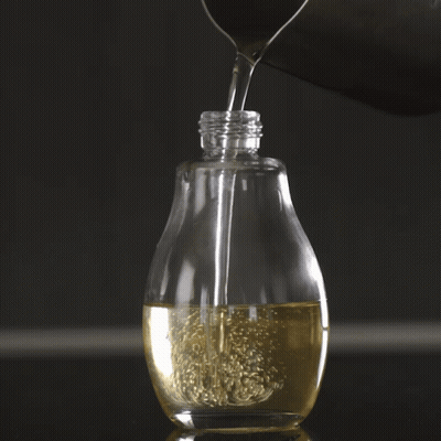 A Clear Bottle Filled With A Yellow Liquid GIF