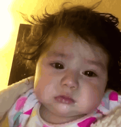 A Close Up Of A Baby 'S Face With A Blanket Around Her GIF