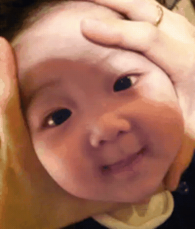 A Close Up Of A Baby 'S Face With A Person Holding It . GIF