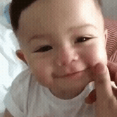 A Close Up Of A Baby 'S Face With A Person 'S Hand On It . GIF