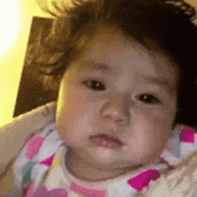 A Close Up Of A Baby 'S Face With A Pink And White Polka Dot Shirt On . GIF