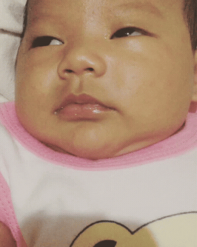 A Close Up Of A Baby 'S Face With A Pink And White Shirt On GIF