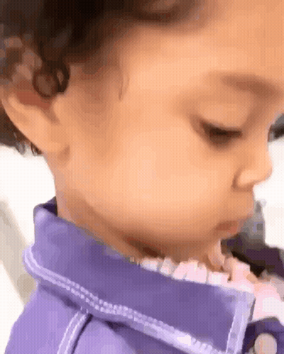 A Close Up Of A Baby 'S Face With A Purple Shirt On . GIF