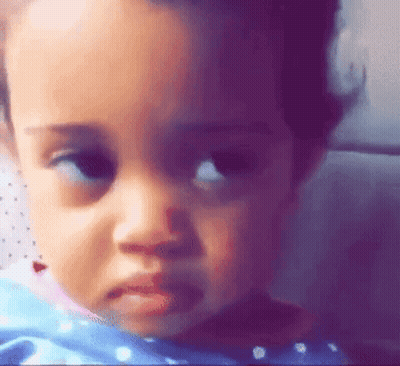 A Close Up Of A Baby 'S Face With A Sad Look On It . GIF