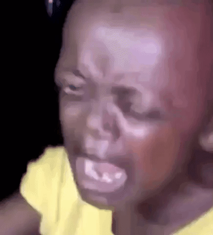A Close Up Of A Baby 'S Face With A Yellow Shirt On Crying . GIF