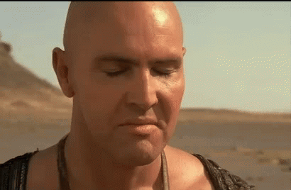 A Close Up Of A Bald Man 'S Face With His Eyes Closed In The Desert . GIF