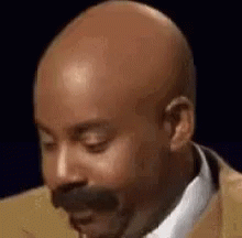 A Close Up Of A Bald Man With A Mustache Wearing A Suit And Tie . GIF