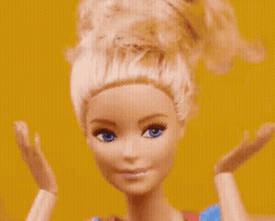 A Close Up Of A Barbie Doll 'S Face With Her Hands Up . GIF