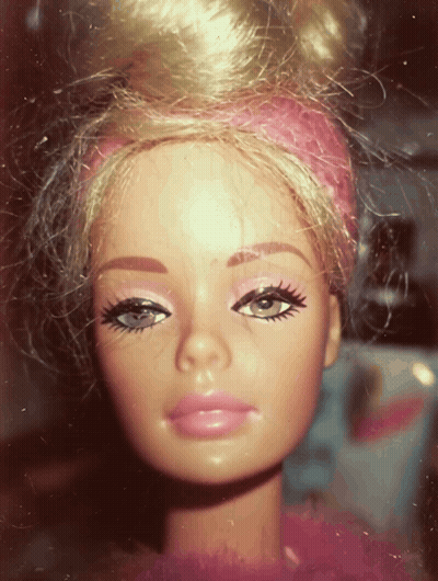 A Close Up Of A Barbie Doll With A Pink Headband On Her Head GIF