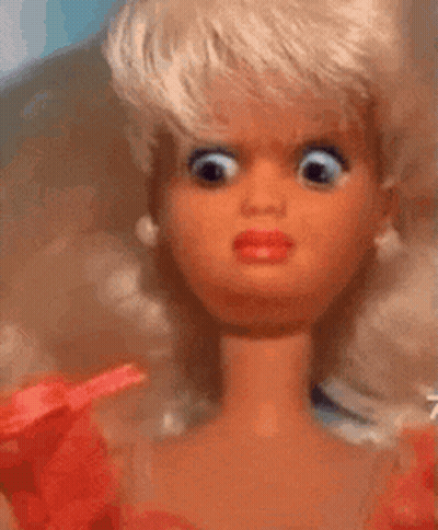 A Close Up Of A Barbie Doll With Big Eyes And A Red Dress . GIF