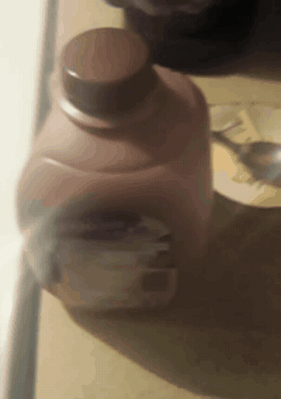 A Close Up Of A Bottle Of Milk With A Spoon In It GIF