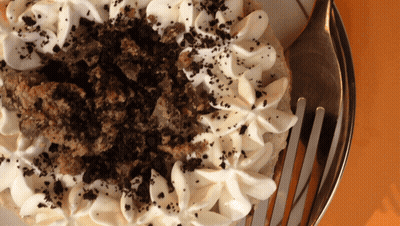 A Close Up Of A Cake With Whipped Cream And Crumbs On Top GIF