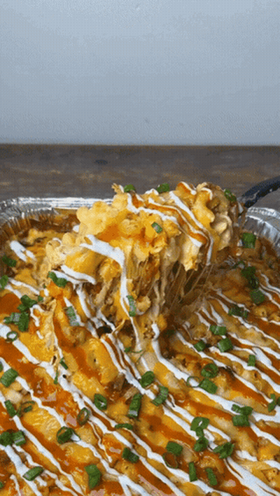 A Close Up Of A Casserole Dish With A Spoon Taking A Bite Out Of It GIF