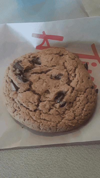 A Close Up Of A Chocolate Chip Cookie On A Piece Of Paper That Says ' Chick-Fil-A ' On It GIF