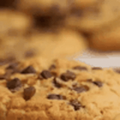 A Close Up Of A Chocolate Chip Cookie On A Plate With Other Cookies . GIF