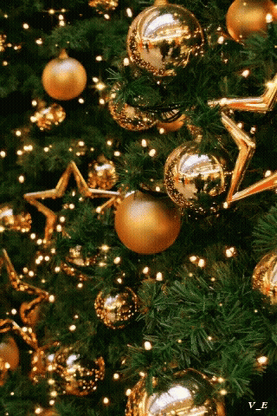 A Close Up Of A Christmas Tree With Gold Ornaments And Lights GIF