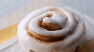A Close Up Of A Cinnamon Roll With Icing GIF