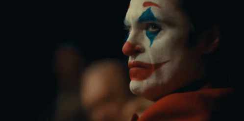 A Close Up Of A Clown 'S Face In A Dark Room . GIF