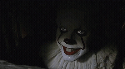 A Close Up Of A Clown With A Smile On His Face In A Dark Room . GIF