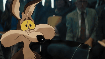 A Close Up Of A Coyote With A Man In A Suit Behind Him GIF