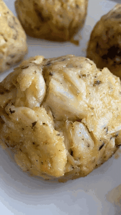 A Close Up Of A Crab Cakes On A White Plate GIF