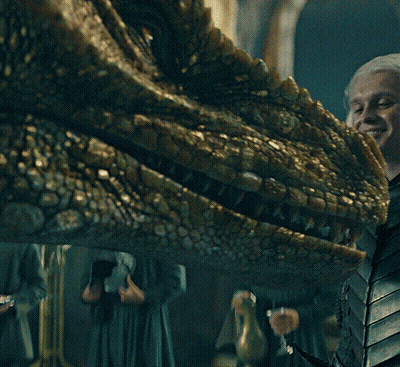 A Close Up Of A Dragon 'S Head With A Woman Holding A Glass Of Wine GIF