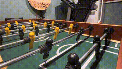 A Close Up Of A Foosball Table With Yellow And Black Players On It . GIF