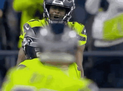 A Close Up Of A Football Player Wearing A Helmet And Holding A Football . GIF