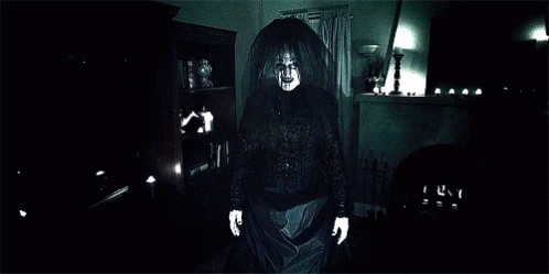A Close Up Of A Ghost With Glowing Hands In A Dark Room GIF