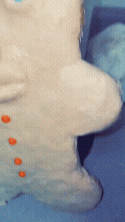 A Close Up Of A Gingerbread Man Covered In Frosting And Orange Buttons GIF