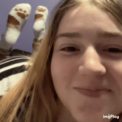 A Close Up Of A Girl 'S Face And Feet With A Paw Print Socks GIF