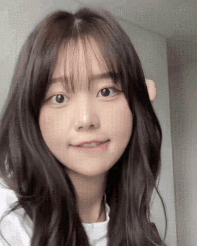 A Close Up Of A Girl 'S Face With Long Hair And Bangs . GIF