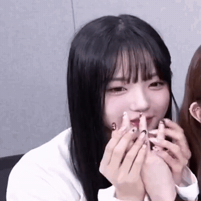 A Close Up Of A Girl With Long Black Hair Holding Her Hands To Her Face . GIF