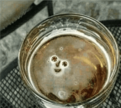 A Close Up Of A Glass Of Beer With A Smiley Face In It GIF