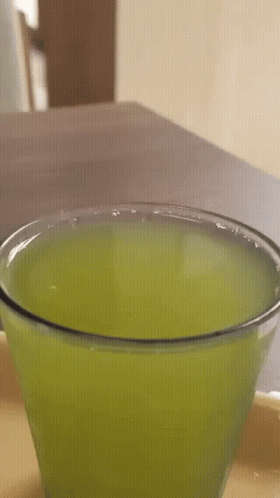 A Close Up Of A Glass Of Green Liquid On A Table . GIF